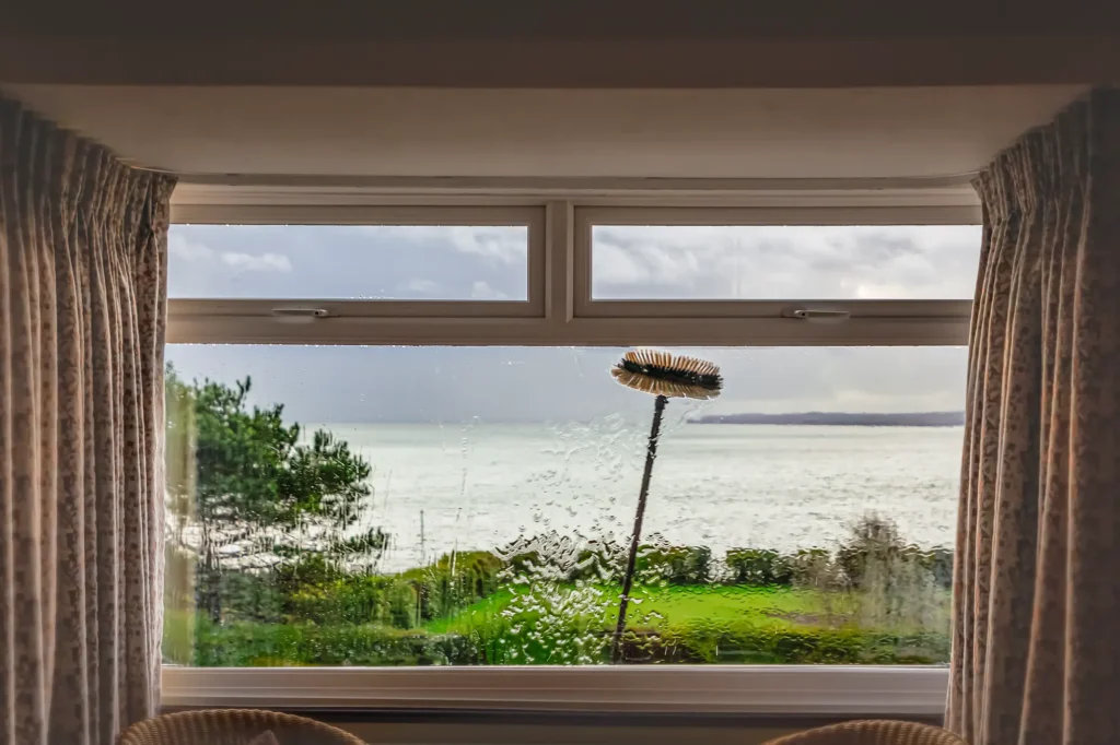 Image of H2Pro window cleaning service showing pressure washer being used on outdoor window
